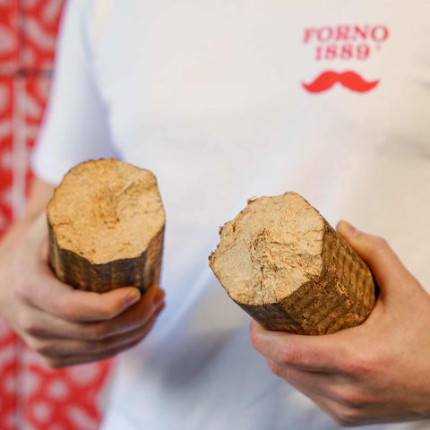 Forno1889® Beechwood Pizza Briquettes held in hand, cut open to show texture – ECOFUEL™