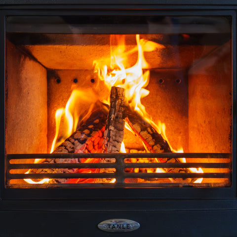 Fireplace with flames and Ecofuel birch wood burning inside, featuring the Stanley brand.