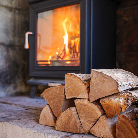 Stack of ECOFUEL Oak firewood in front of a lit fireplace