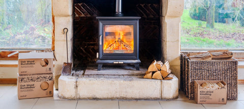 A warm fire burning in a wood-burning stove, with firewood ready for the colder days.