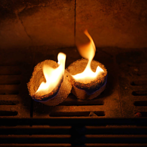 Two natural firelighters are burning in a fireplace with a warm glow.